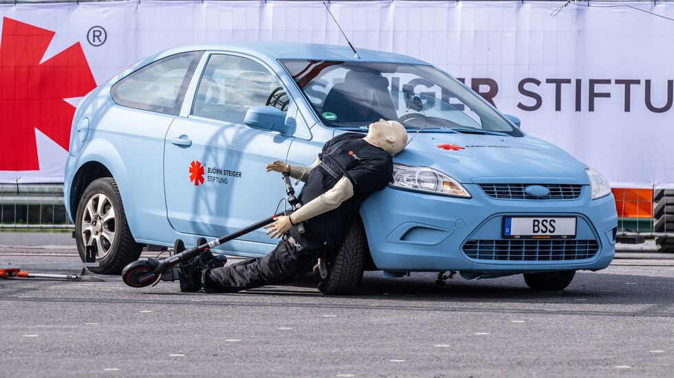 Crashtest mit einem E-Scooter: Ein abbiegendes Auto erfasst den Dummy - der prallt hart auf den Wagen. Crashtest mit einem E-Scooter: Ein abbiegendes Auto erfasst den Dummy - der prallt hart auf den Wagen.