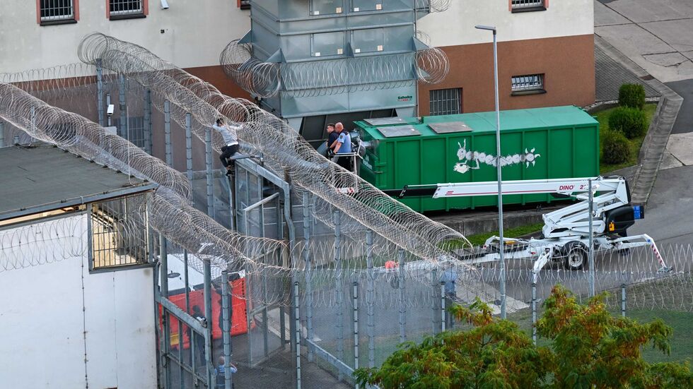 Der Häfling klammert sich fest, wird in wenigen Augenblicken ins Rettungskissen springen. Das Ende der Flucht.