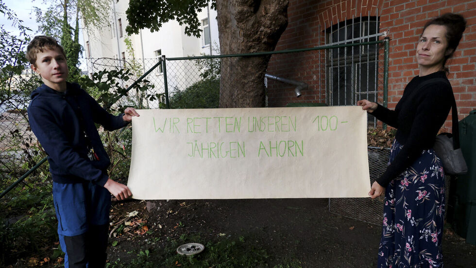 Elzbeta Laabs mit ihrem Sohn und einem Plakat am alten Ahorn.
