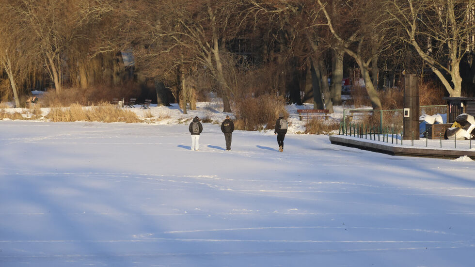Menschen spazieren über den zugefrorenen Schlossteich Menschen spazieren über den zugefrorenen Schlossteich