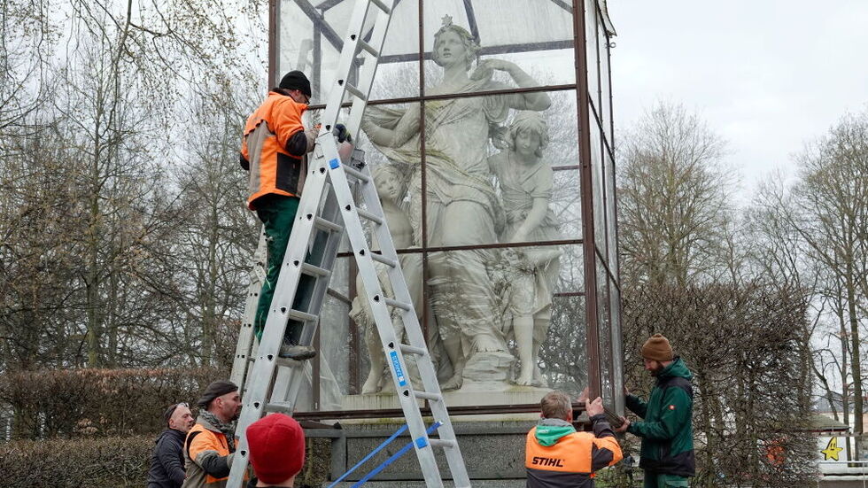 Mitarbeiter des Grünflächenamtes hieven die Einhausungen von den Figuren.