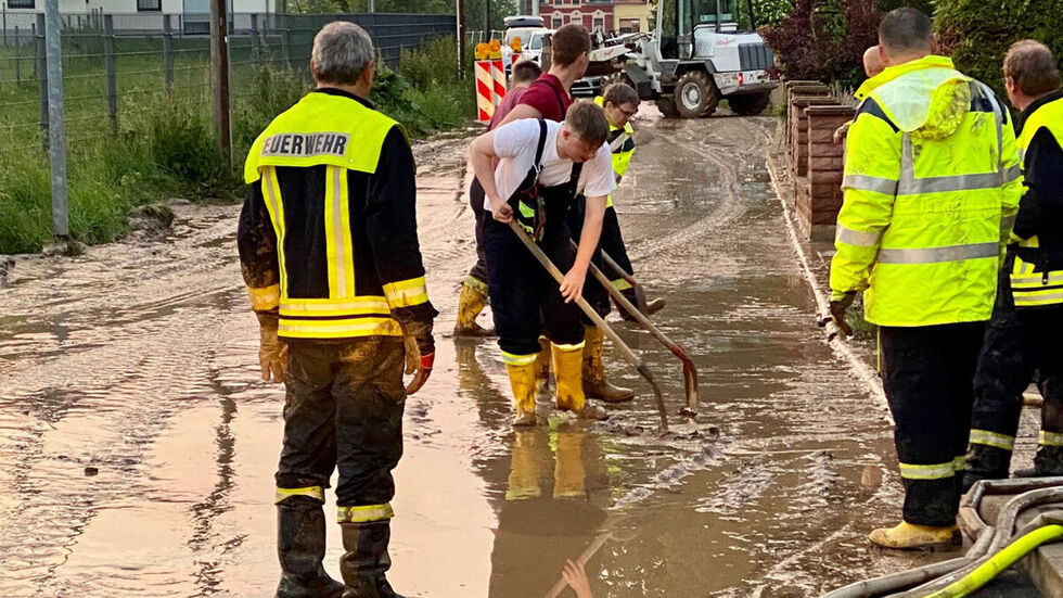 Feuerwehrleute schaufeln Schlamm von der Straße. Feuerwehrleute schaufeln Schlamm von der Straße.