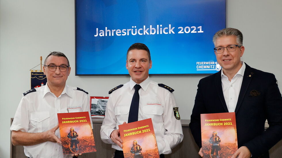 Feuerwehrchef Rene Kraus (mitte) und der Vorsitzende des Stadtfeuerwehrverbandes Thomas Jacob (links) übergaben das Jahrbuch an Bürgermeister Ralph Burghart (rechts).